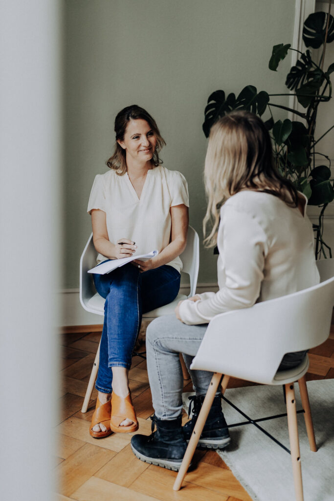Personal Branding Foto einer Coachin, die eine Clientin anlächelt, die ihr gegenüber sitzt