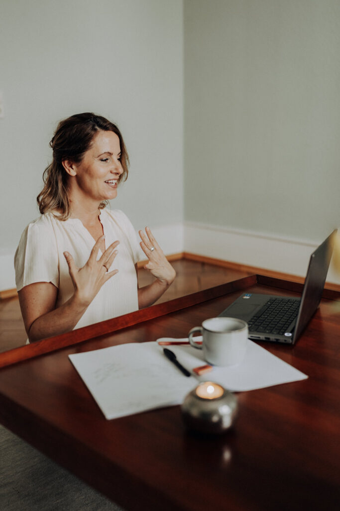 Personal Branding Foto einer Coachin, die am Schreibtisch sitzt und in ihren Laptop spricht