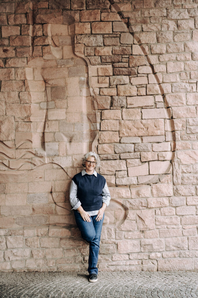 Personal Branding Foto einer Ärztin, die vor einer großen Sandsteinwand in Freiburg steht