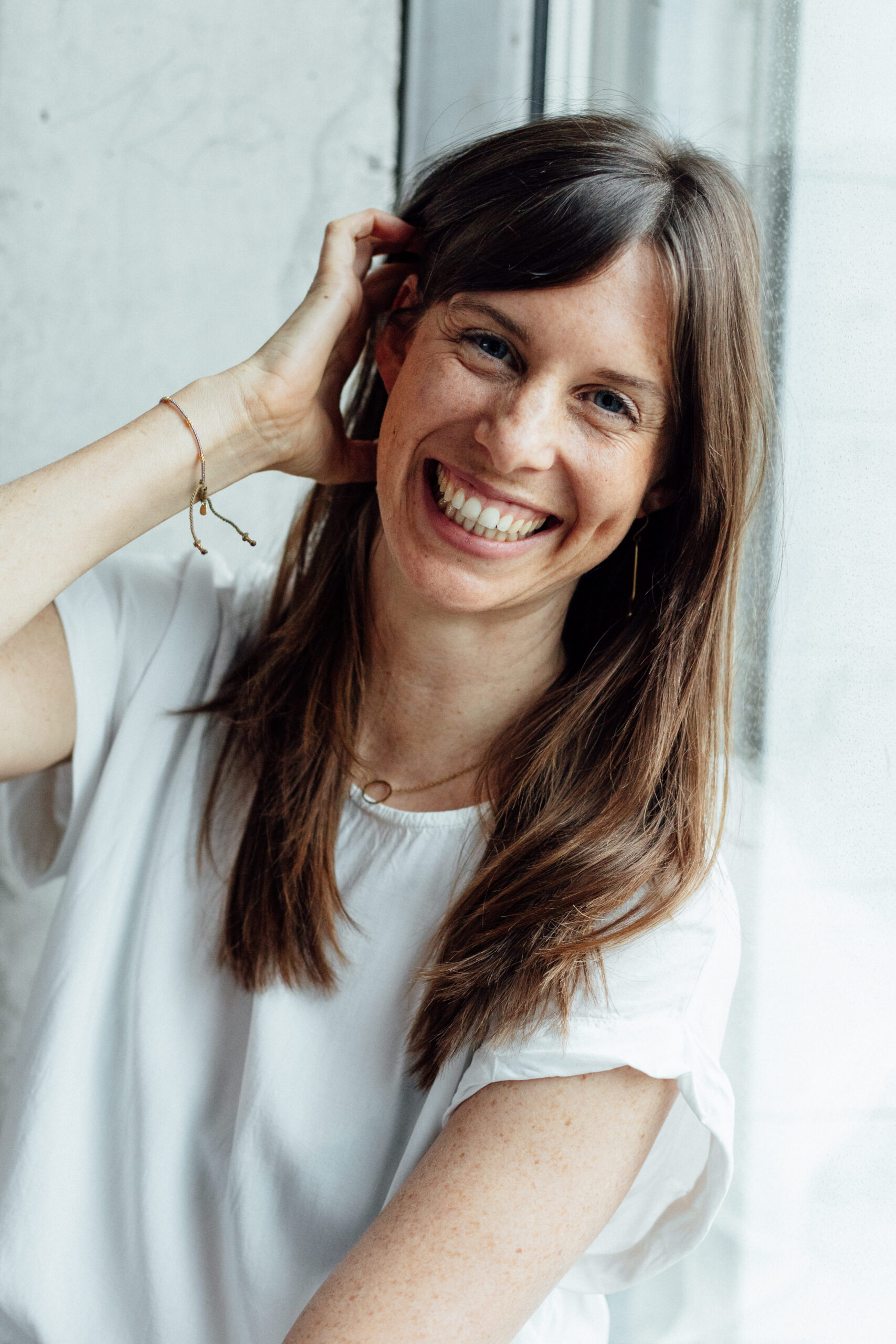 Luisa steht angelehnt an einer Wand und lächelt auf ihre Kamera